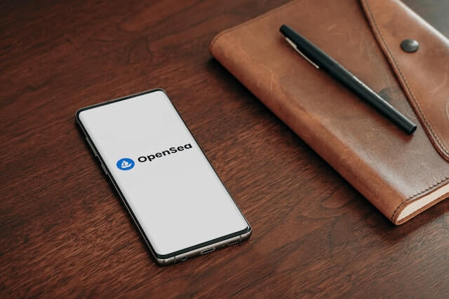 OpenSeaが表示されたスマートフォンとペンと手帳